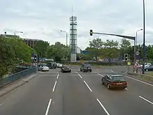 Four lanes of traffic approach a set of traffic lights.