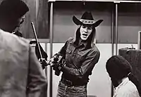  Photograph of Sahm holding a fiddle and bow talking to a man in a recording studio