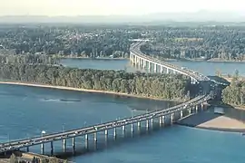 Aerial view of a highway bridge on columns crossing a river and a narrow island.