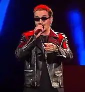 J Balvin, facing front, holding a microphone.