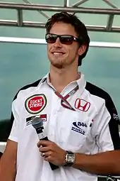 Jenson Button wearing a white T-shirt with sponsors logos and black sunglasses