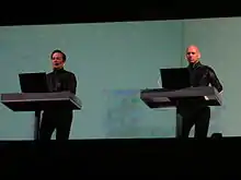 Kraftwerk performing onstage, standing on two separate dais.