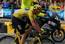 A man wearing a yellow jersey riding a bicycle.