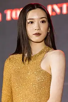 Nagano at press event facing camera with arms at sides