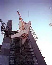 The Space Shuttle Orbiter simulator is hoisted into the Saturn V dynamic test stand in 1977