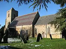 A stone church seen from the southeast, showing the chancel and the nave with a tower at the far end