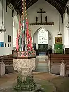 The tall ornate font cover of the font dates from the 20th century and originates from the parish church in Buxton, Norfolk.
