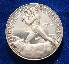 The reverse of a World War I  German Silver medallion liberation of East Prussia 1914 by Paul von Beneckendorff und von Hindenburg. Referring to the Battle of Tannenberg. The naked General Hindenburg fighting the Russian Bear with his sword.